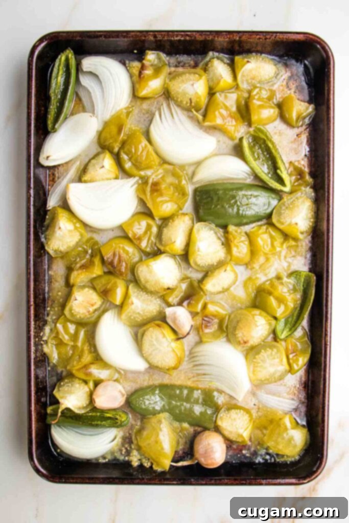 Zesty Roasted Tomatillo Salsa 7 Roasted tomatillos, jalapenos, onions, and garlic on a baking sheet after roasting.