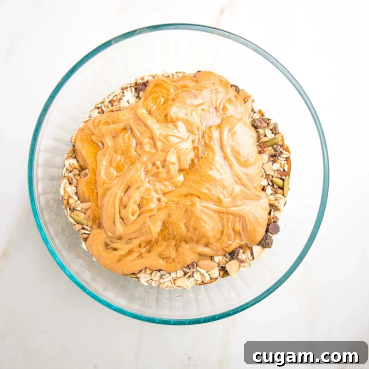 Peanut butter mixture on top of oats, nuts, seeds, raisins, and chocolate chips.