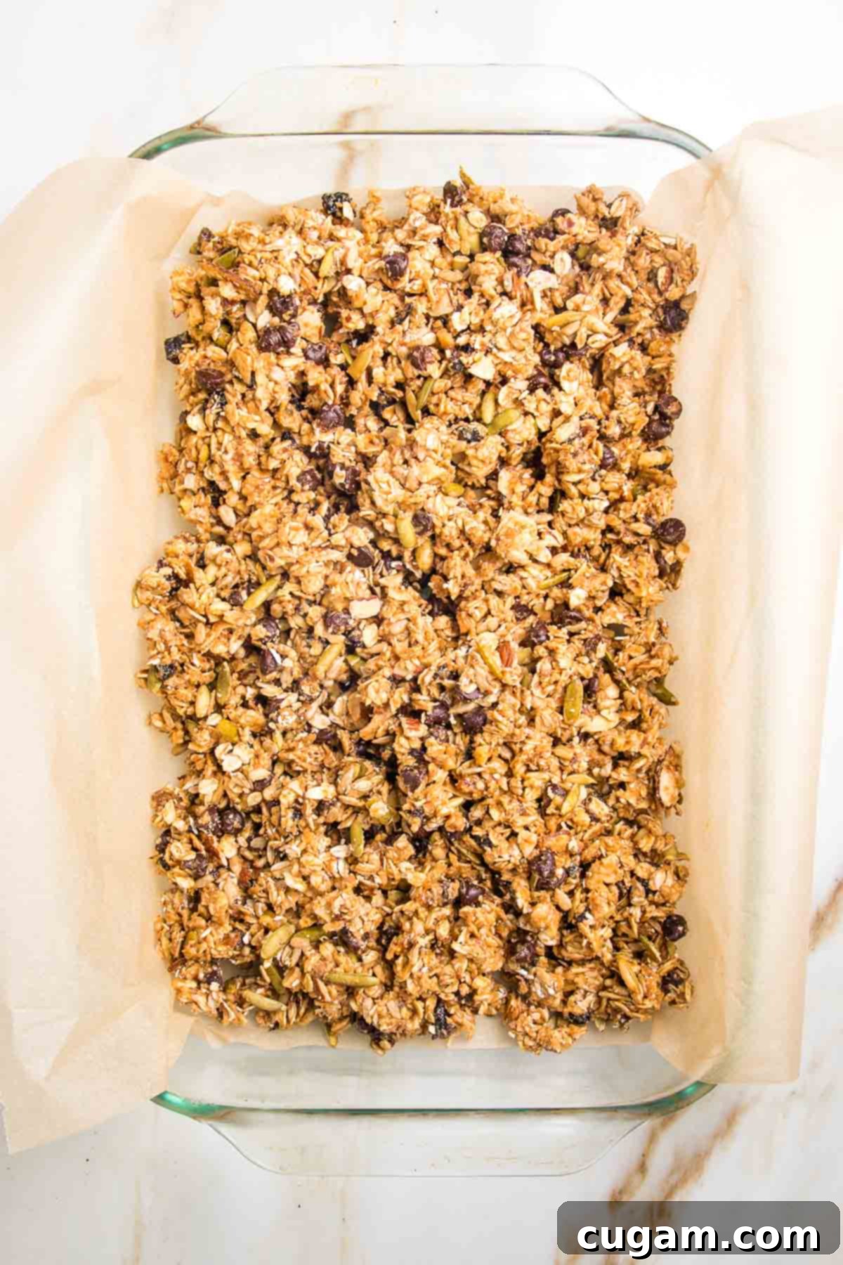 Granola Bar mixture spread into glass baking dish lined with parchment