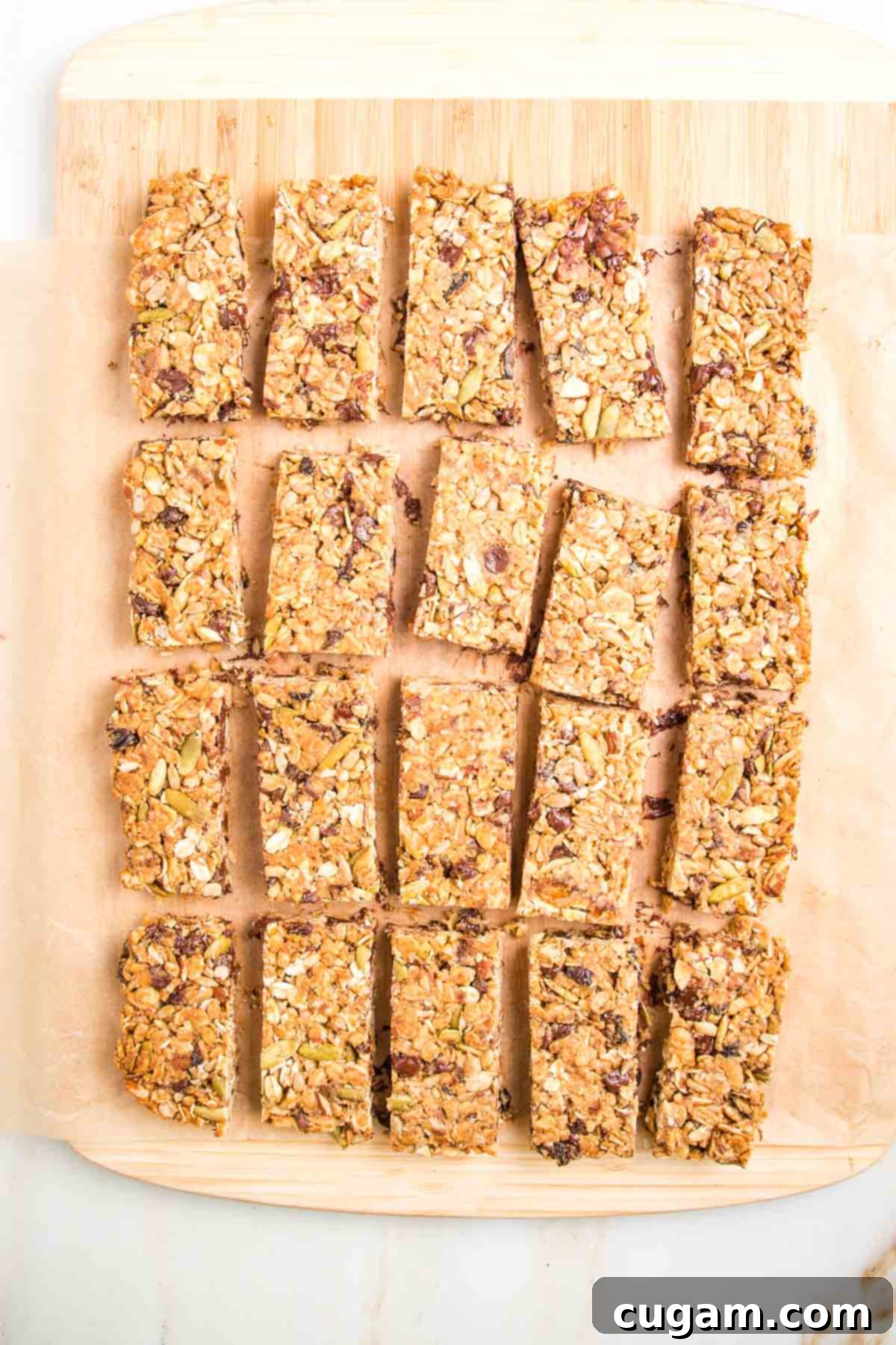 Crunchy granola bars on a sheet of parchment atop a wooden board.