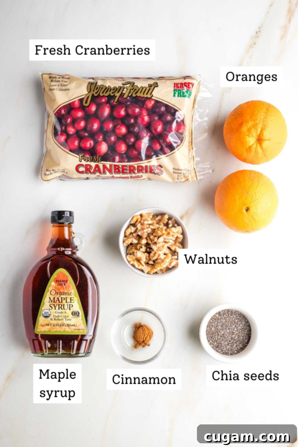 Labeled ingredients for cranberry sauce: fresh cranberries, oranges, maple syrup, walnuts, cinnamon and chia seeds.