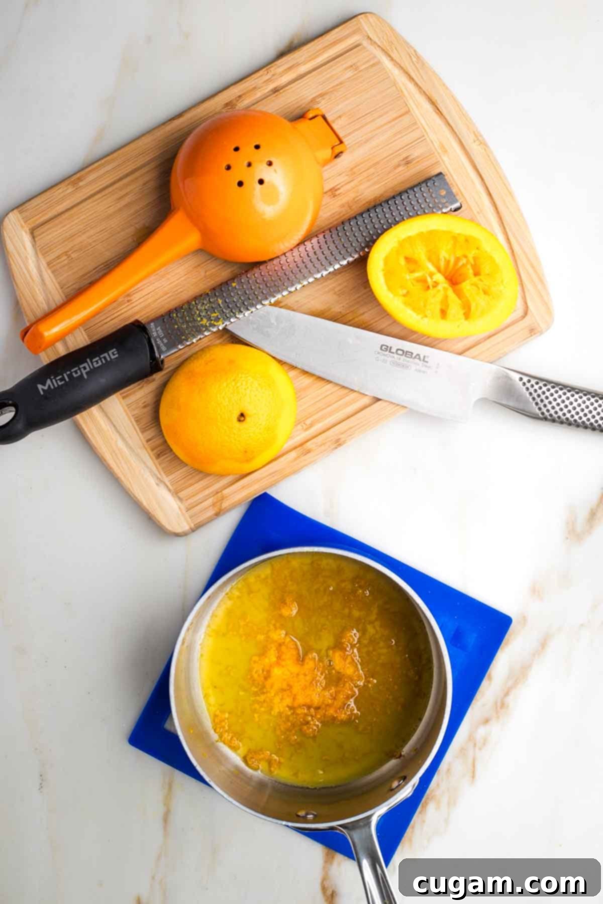 Orange zest and juice in a small saucepan with the tools and spent oranges in the background.