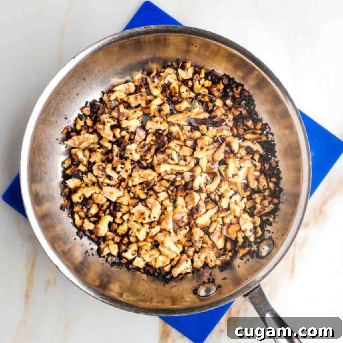 Chopped walnuts toasting in a small skillet.
