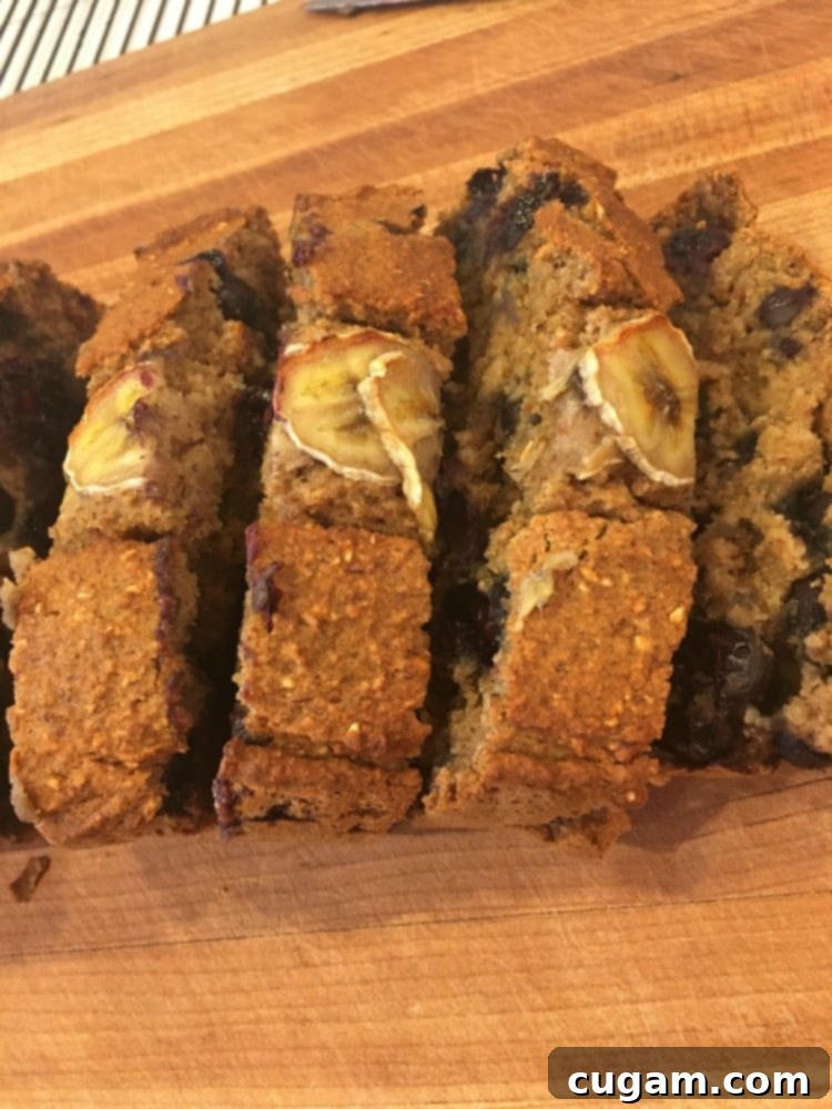 Overhead view of a loaf of healthy banana bread, artfully sliced and topped with fresh banana pieces.