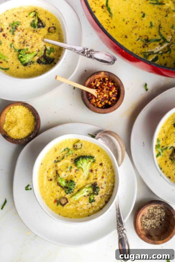 Bowls of creamy yellow soup with chunks of crispy broccoli and pepper floating on the surface.