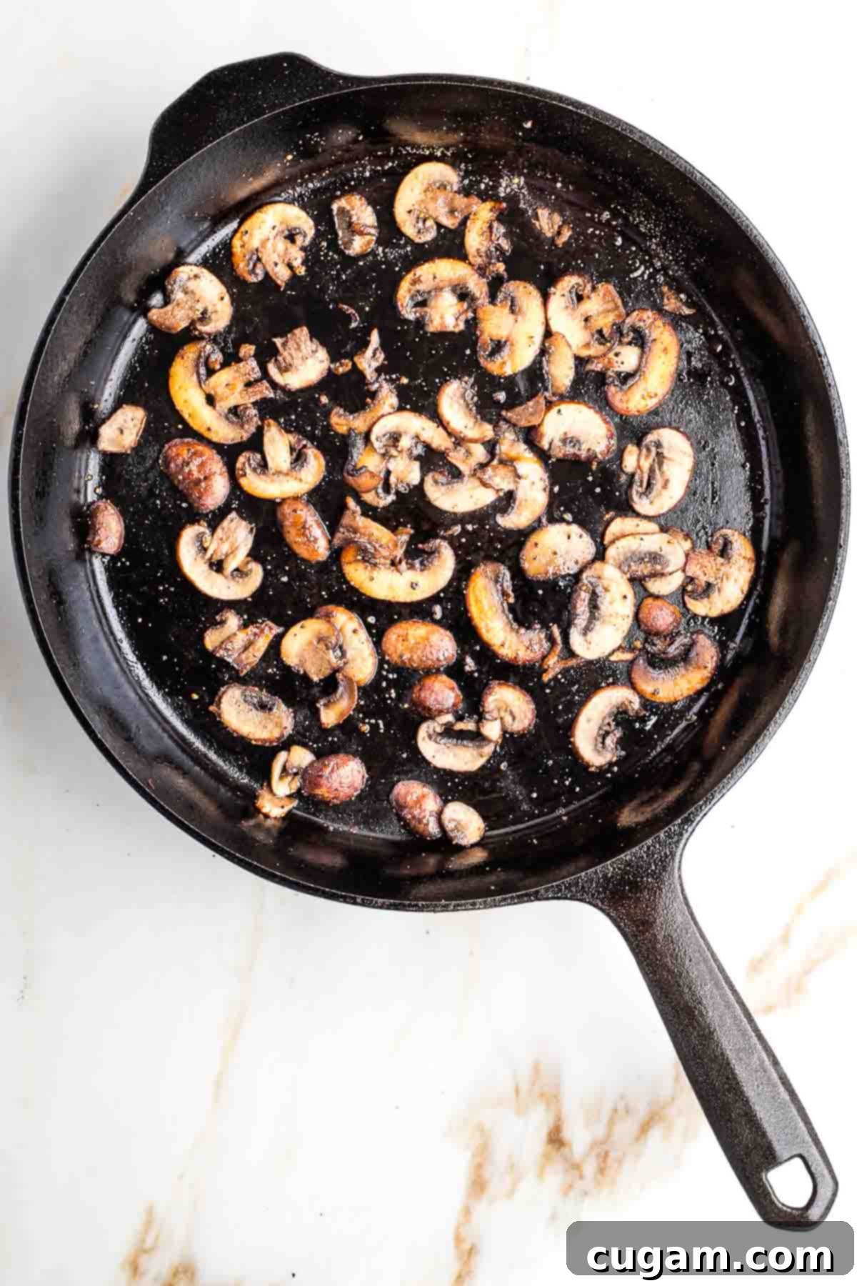 Sliced portobello mushrooms in a cast iron skillet.