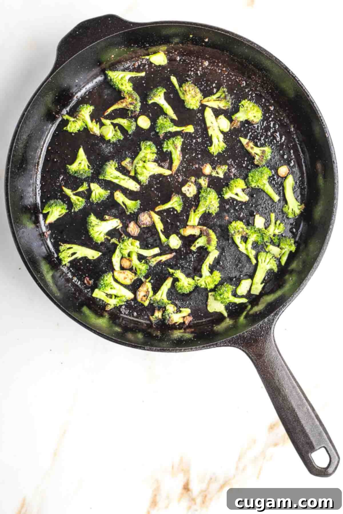 Broccoli florets and diced stems in a cast iron skillet.