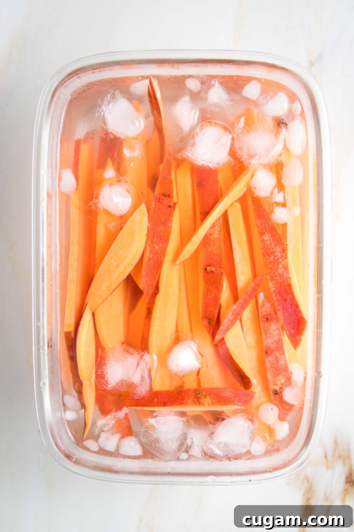 Slices of sweet potatoes soaking in ice water.