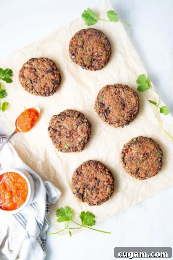 Parchment paper with veggie burgers and a bowl of red sauce to spoon on top.