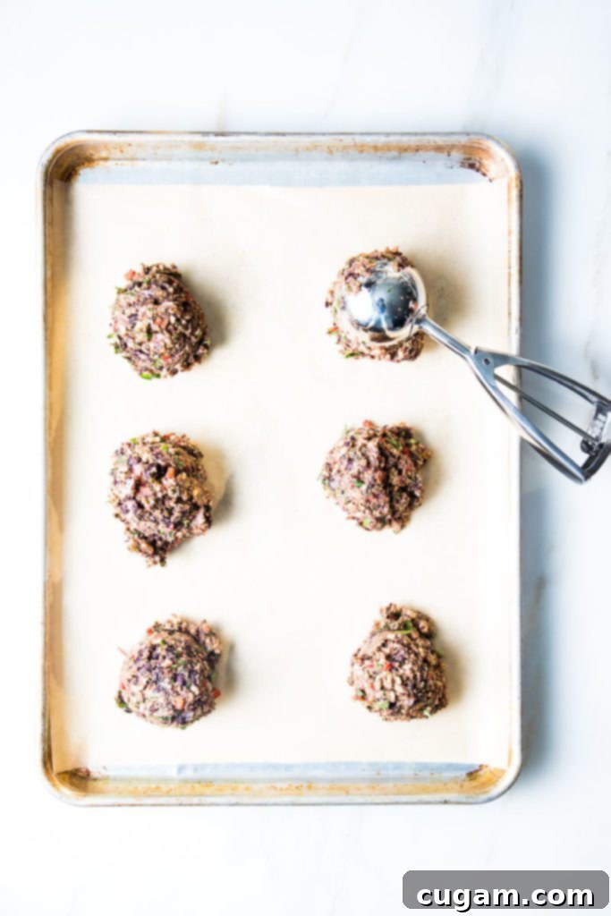 Scoops of veggie burger dough on a baking tray lined with parchment paper.