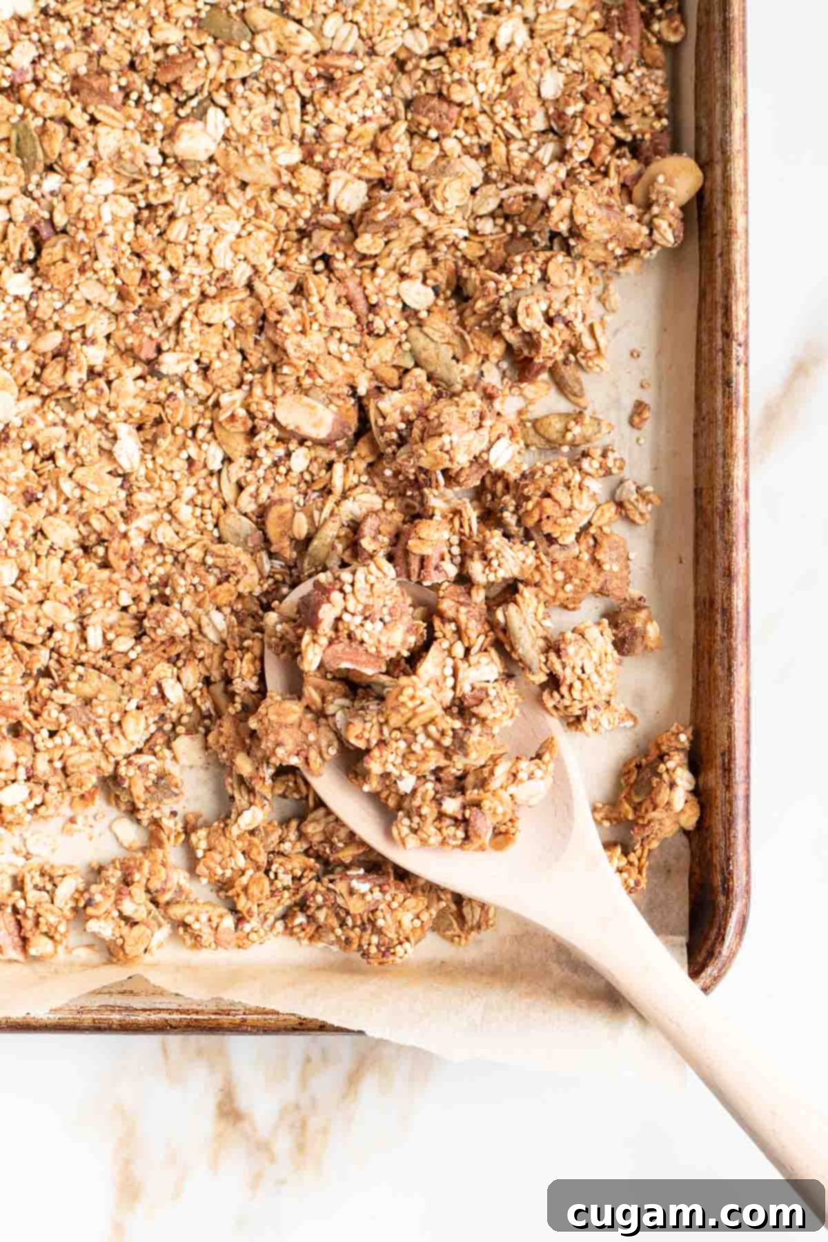 Corner of a large baking tray with a spoonful of homemade granola, ready for serving.