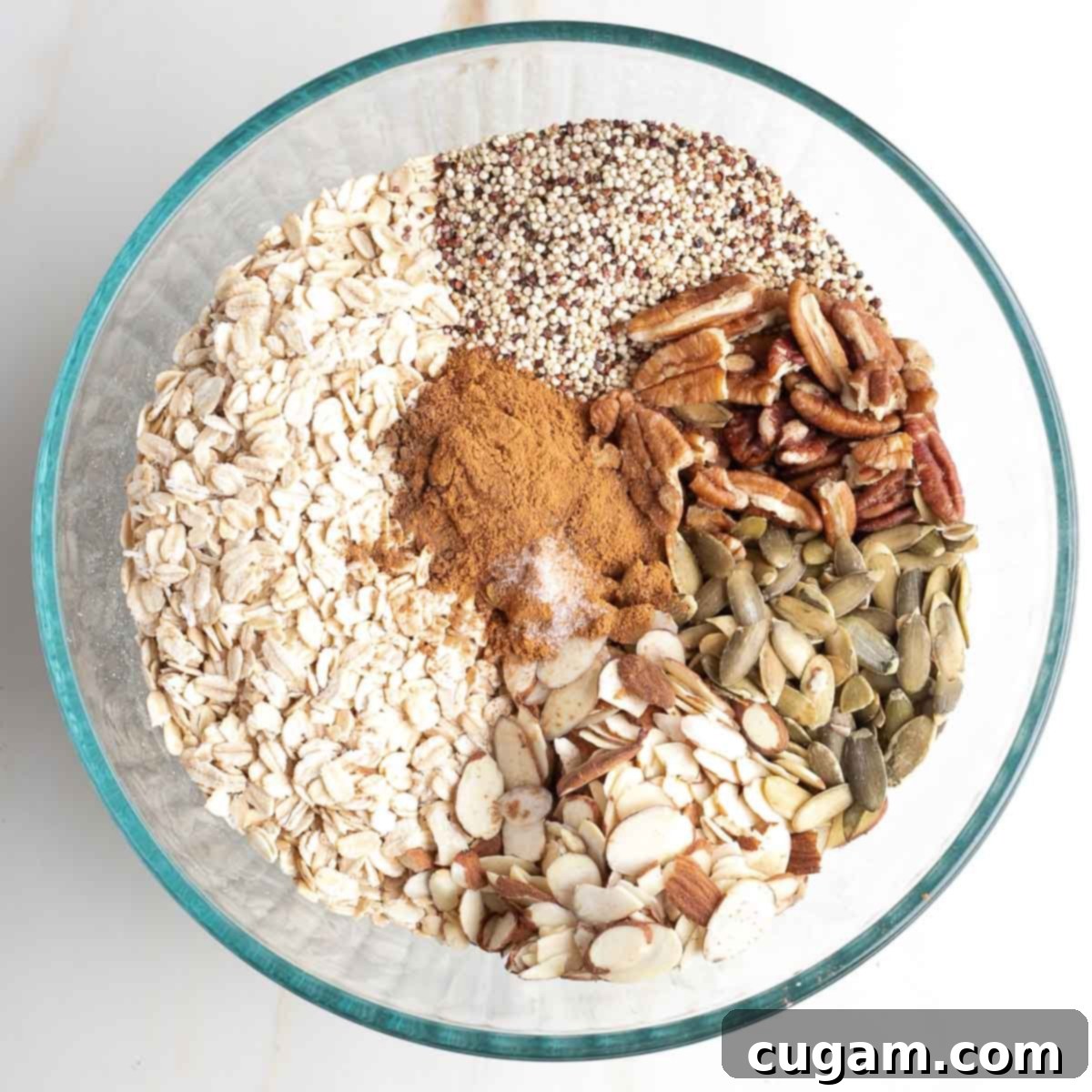 Oats, nuts, seeds and spices in a large bowl, ready to be mixed.