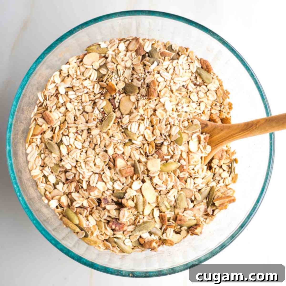 Dry ingredients mixed together in a large bowl with oats, nuts, seeds and spices, showing the uniform blend.
