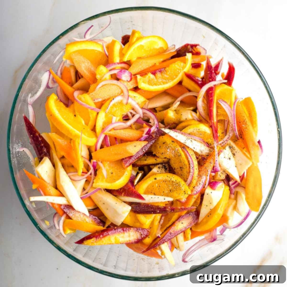 Bowl of brightly colored carrots, parsnips, oranges and onions in a bowl.