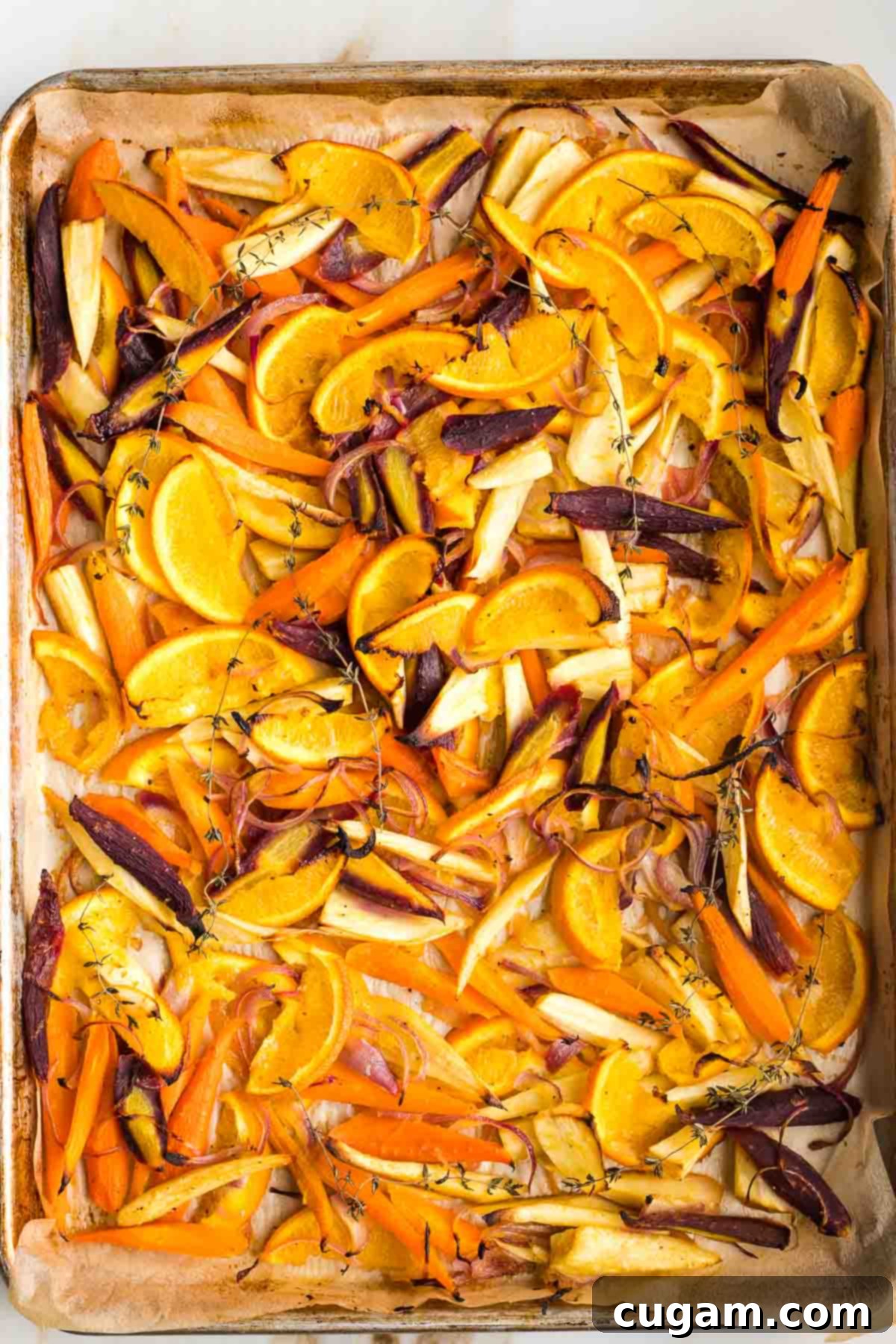 Honey roasted parsnips, carrots, oranges and onions on a parchment lined baking tray. 