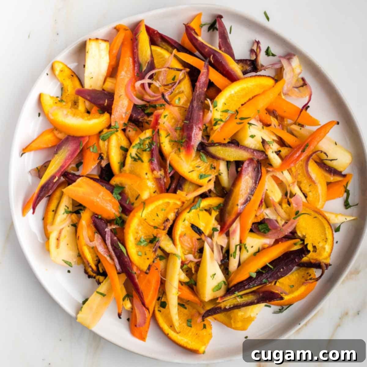 Plate filled with colorful roasted carrots and parsnips with oranges.