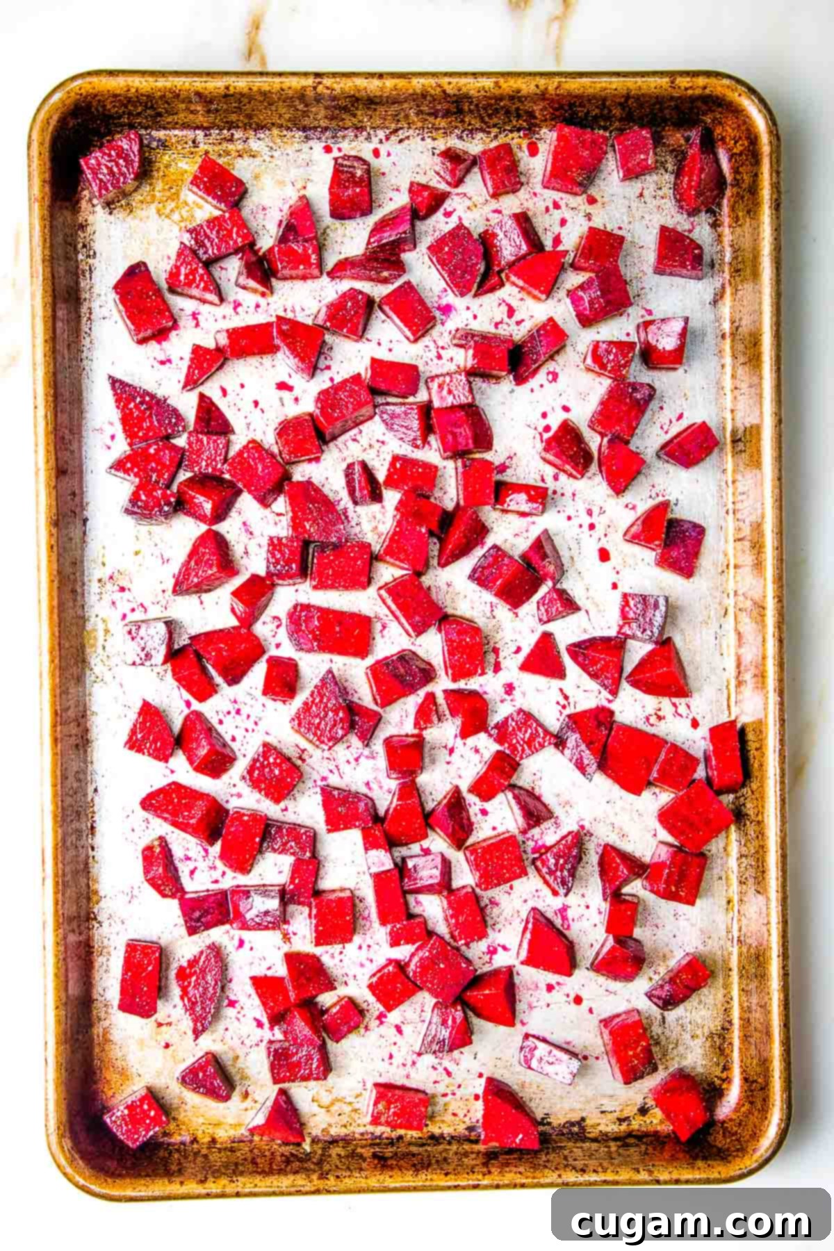 Small cubes of red beetroot on a rimmed baking sheet.