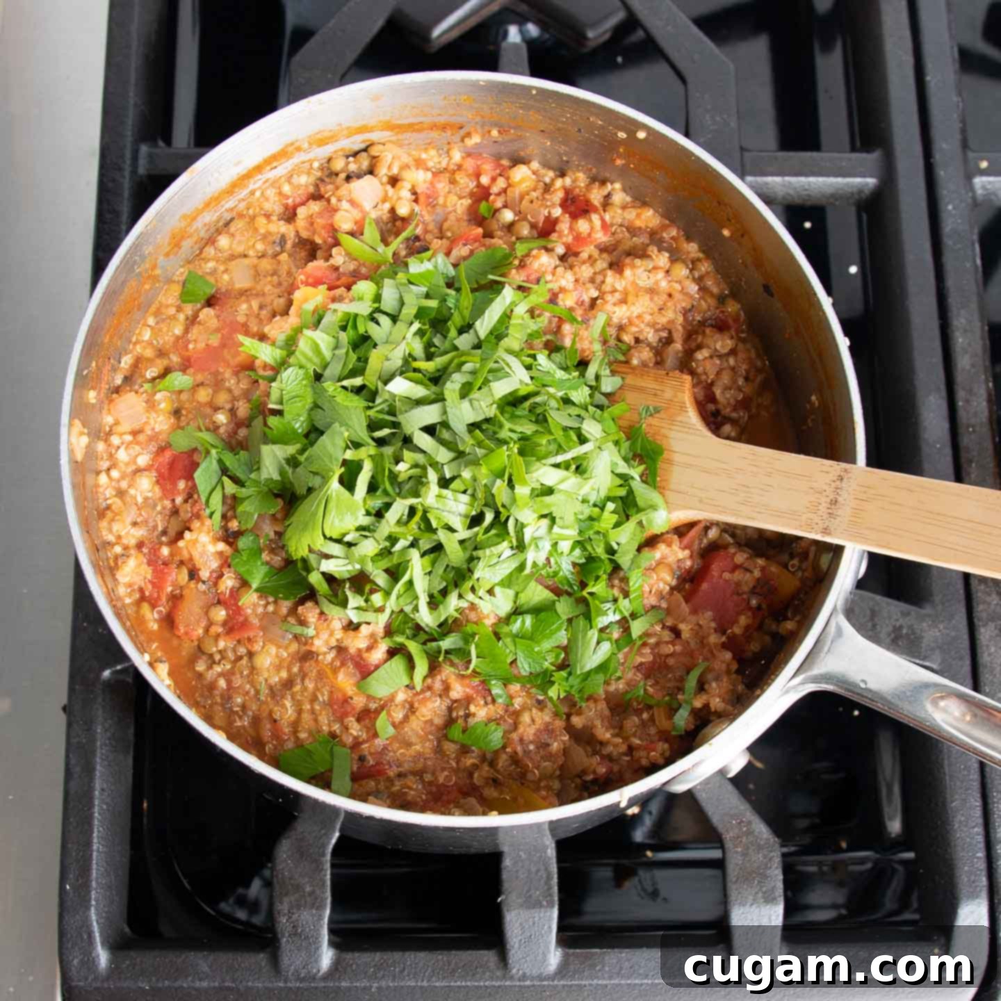Nutritional yeast and ground flaxseeds being stirred into the cooked quinoa and lentil mixture.