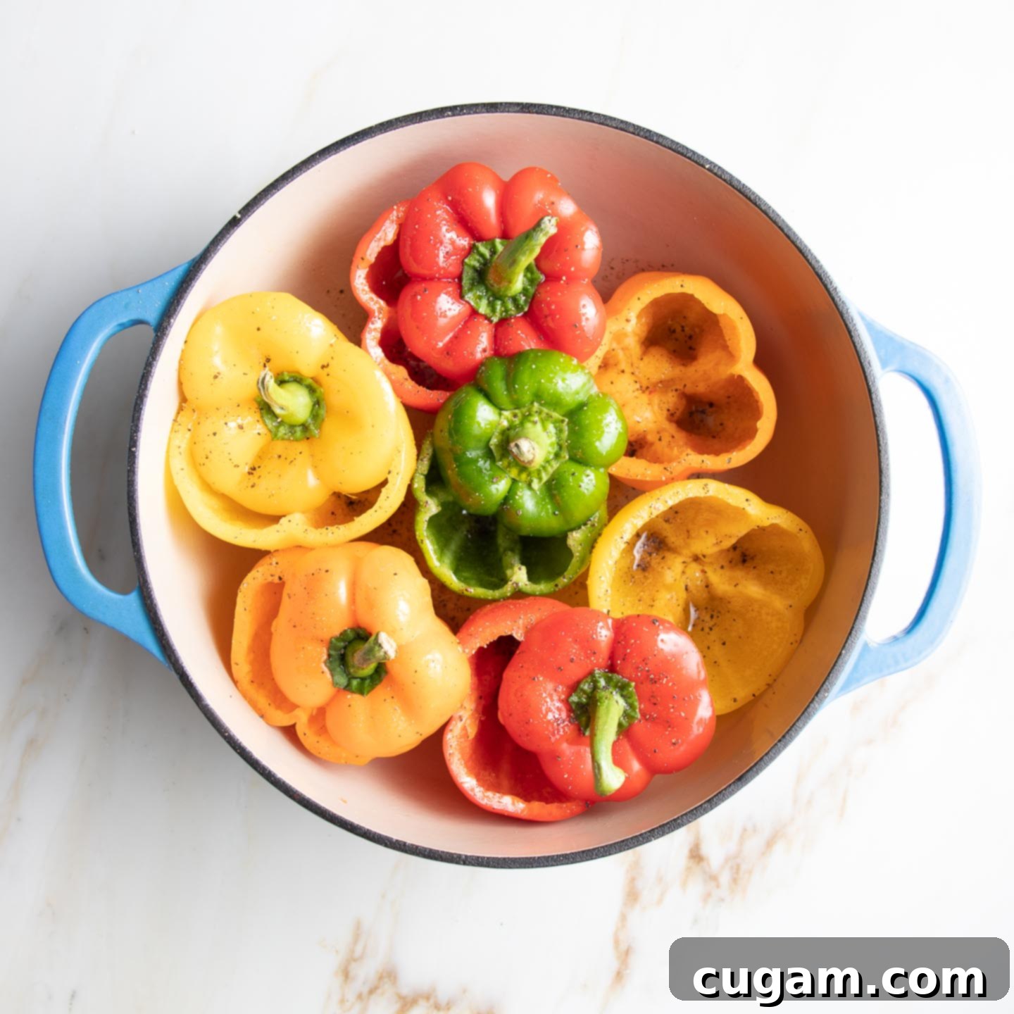 Red, orange, yellow and green bell peppers, with their tops cut off, fit tightly into a dutch oven ready for par-baking.