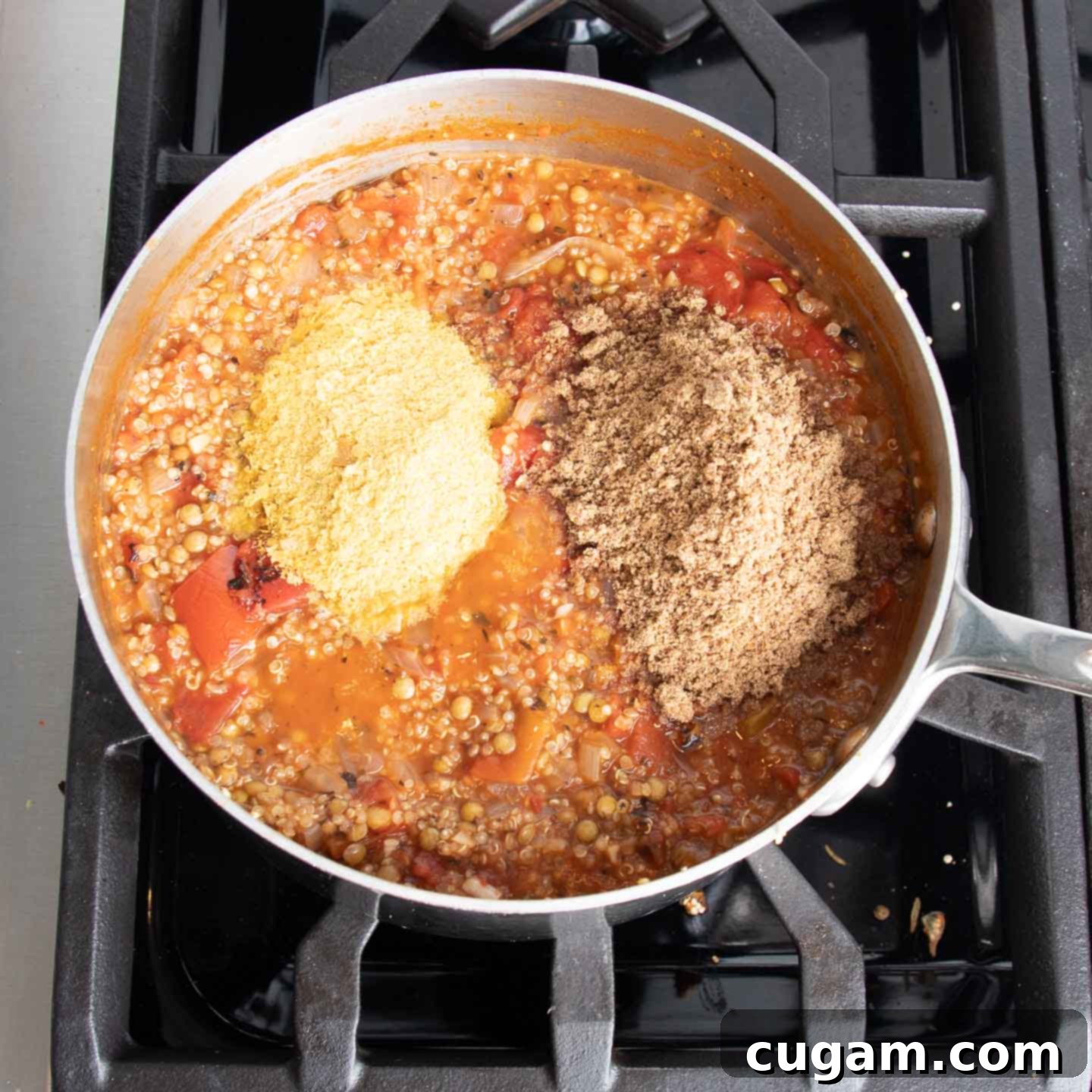 Vegetable stock added to the quinoa, lentils, and tomatoes mixture, simmering on the stovetop.