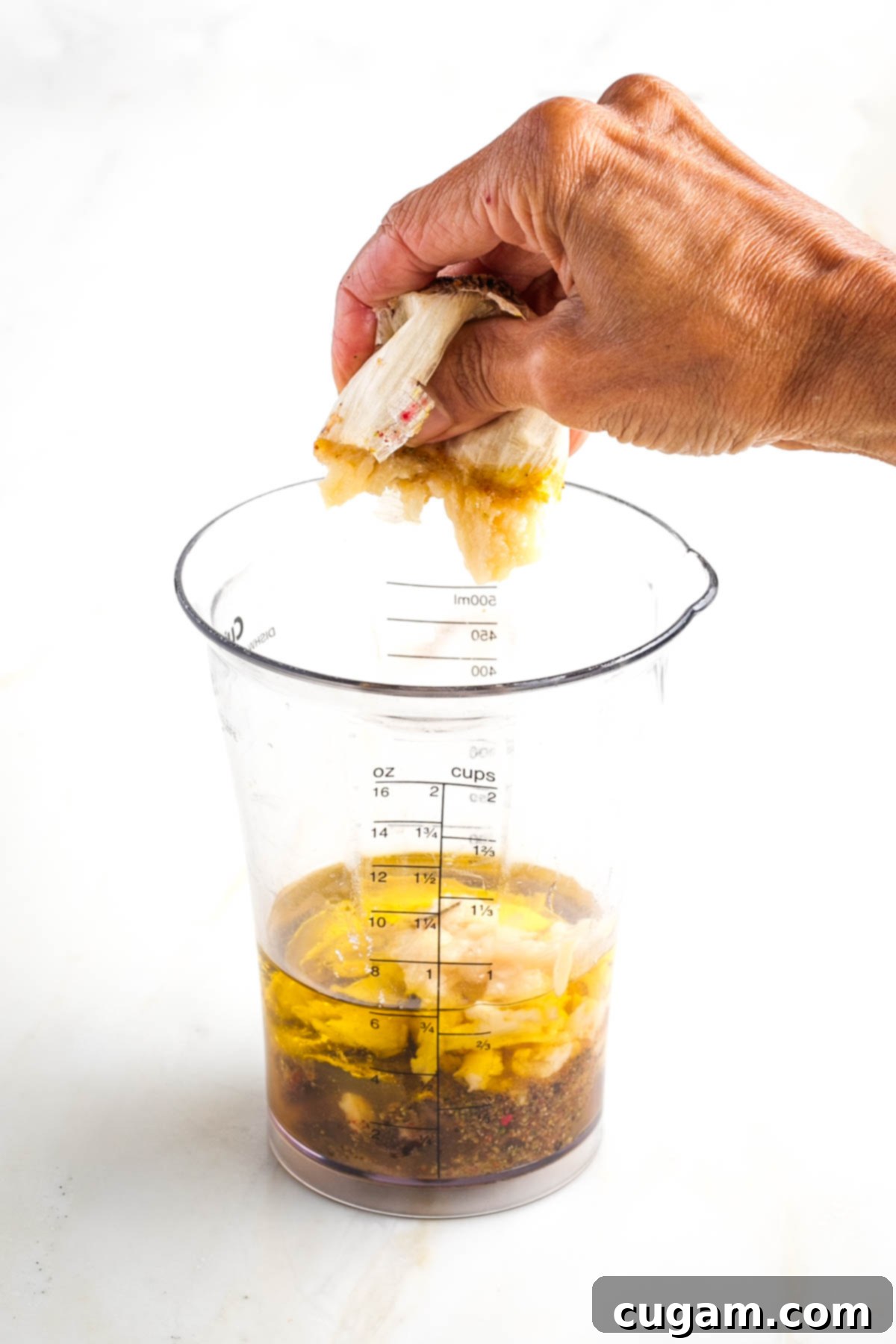 Squeezing roasted garlic pulp into a blender cup.