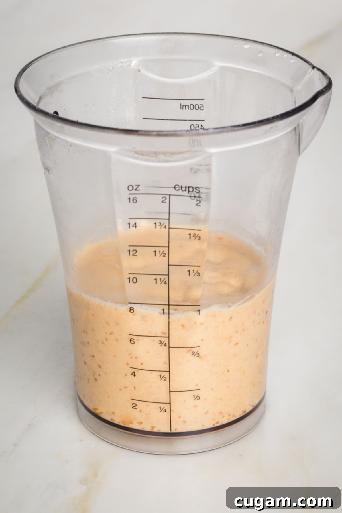 Adding water to thicken dressing in a blender.