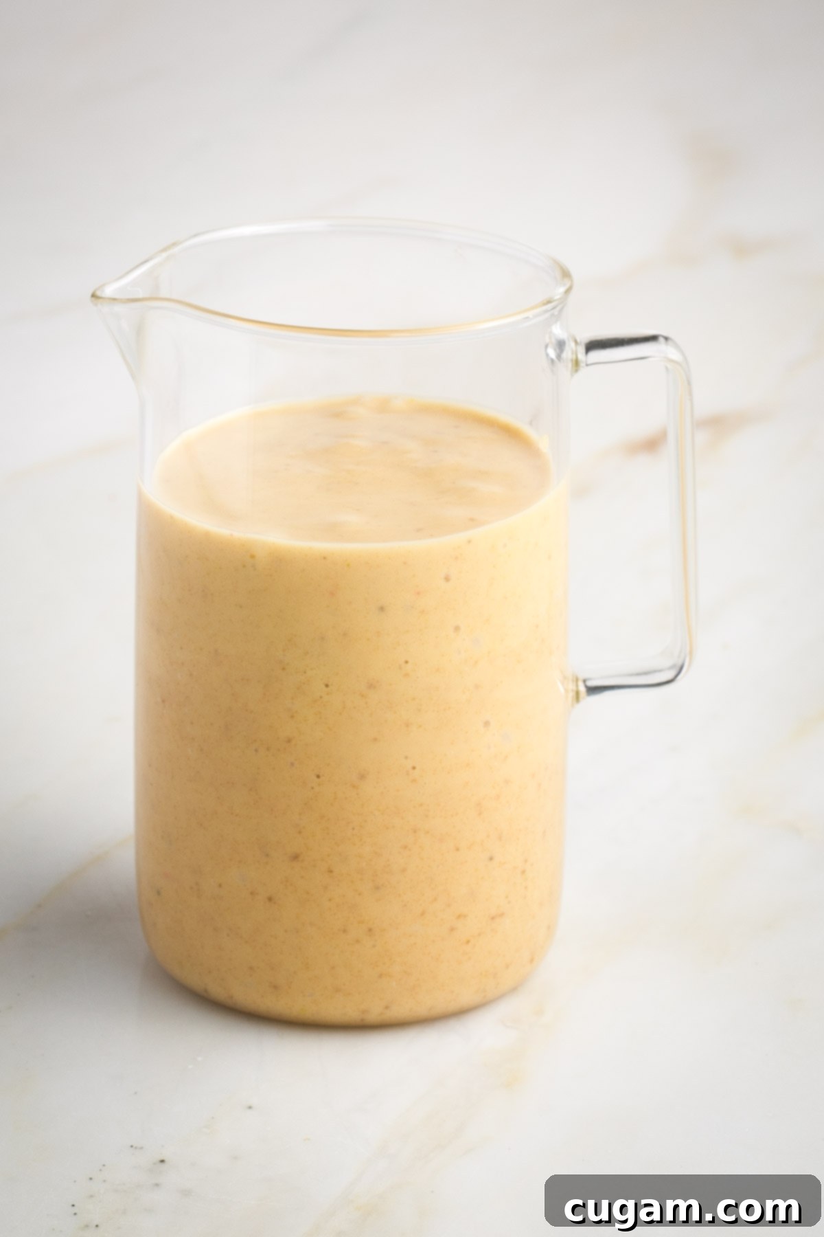 Two heads of roasted garlic, one squeezed empty, next to a jar of creamy dressing.