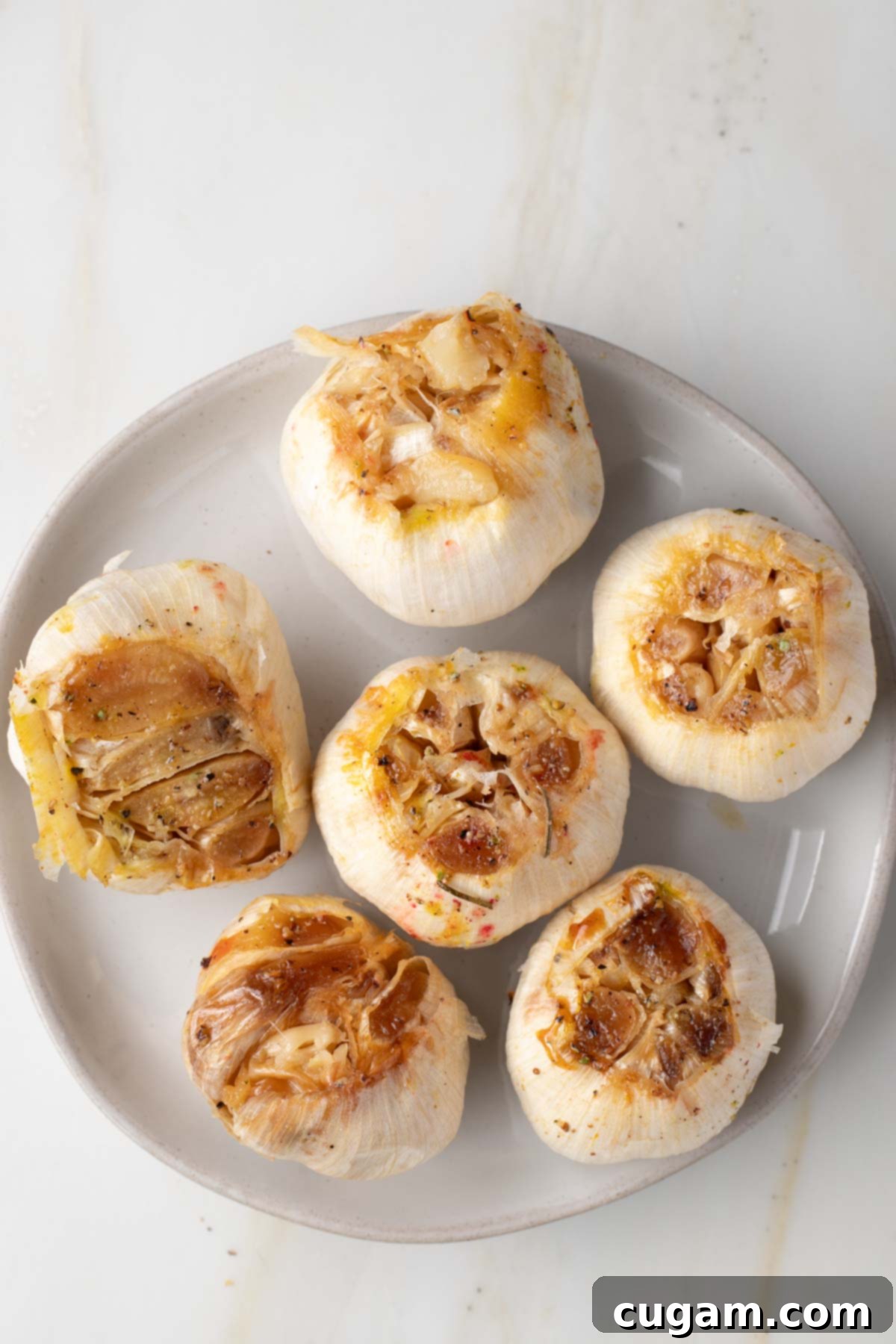 Whole roasted bulbs of garlic on a plate.