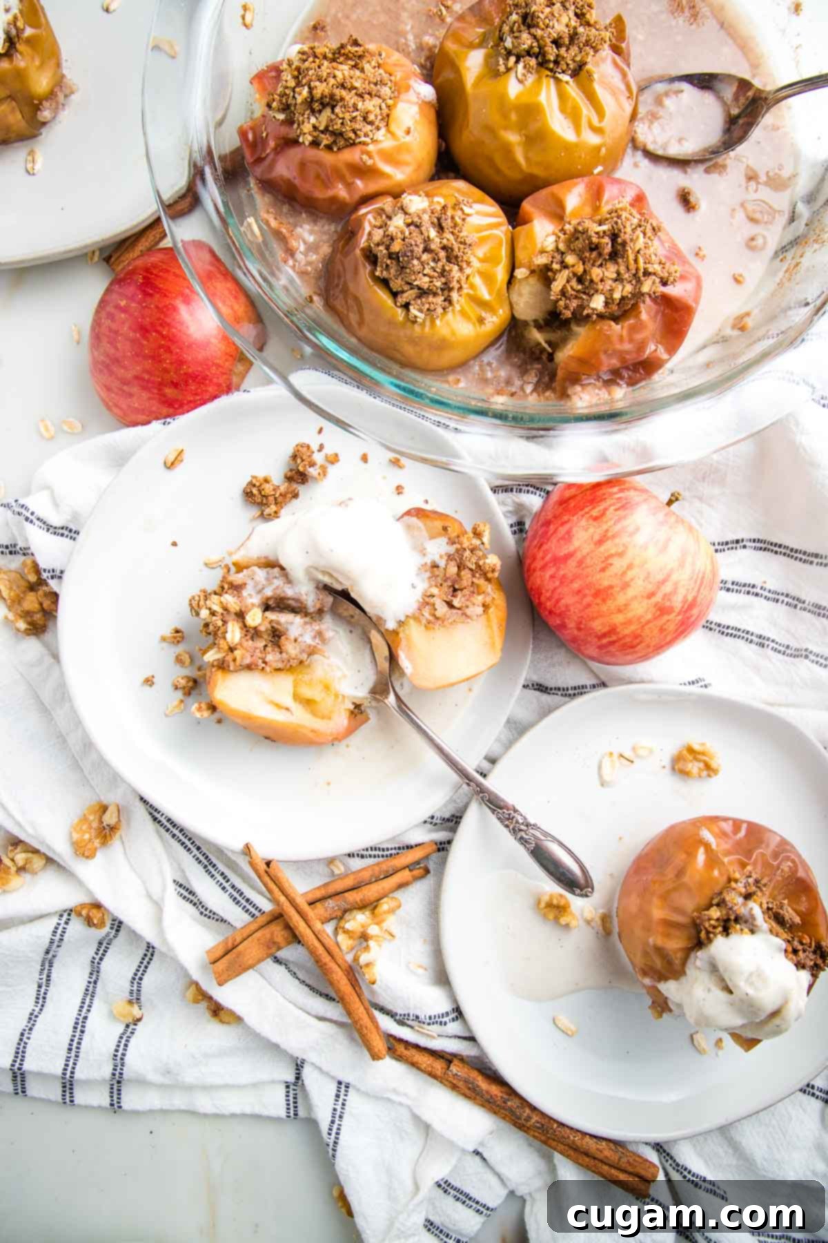 Baked apples in a pie dish and on a plate, cut in half and topped with ice cream.