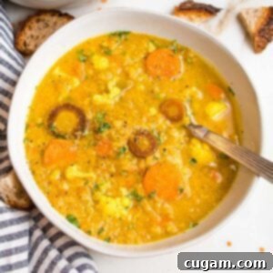 Large white bowl filled with thick and creamy red lentil soup that also has chunks of cauliflower and carrots.