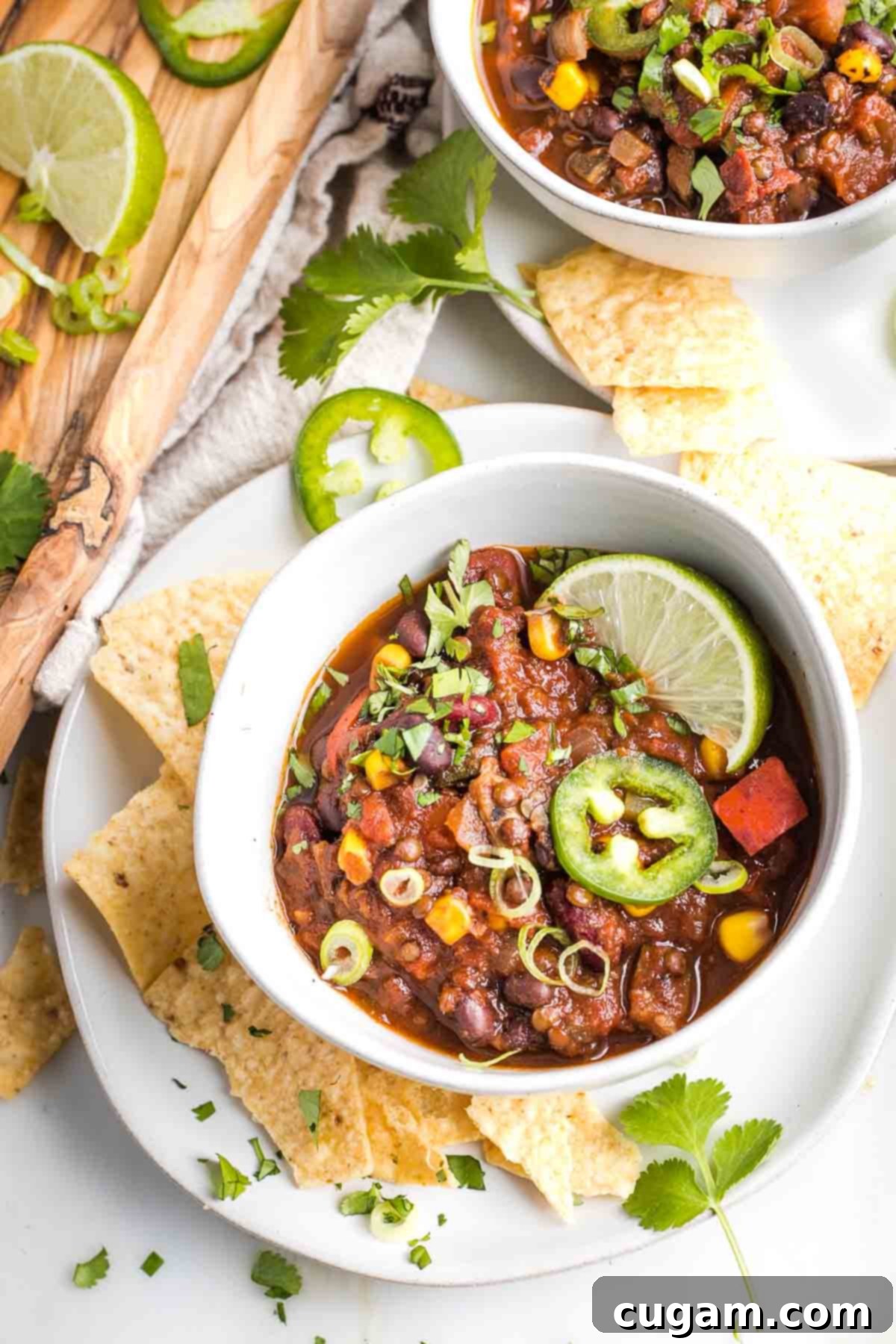 Quick and Easy Vegan Lentil Chili 2 Bowl of vegan chili with lentils, beans and corn. Garnished with lime, jalapeno, cilantro and chips.
