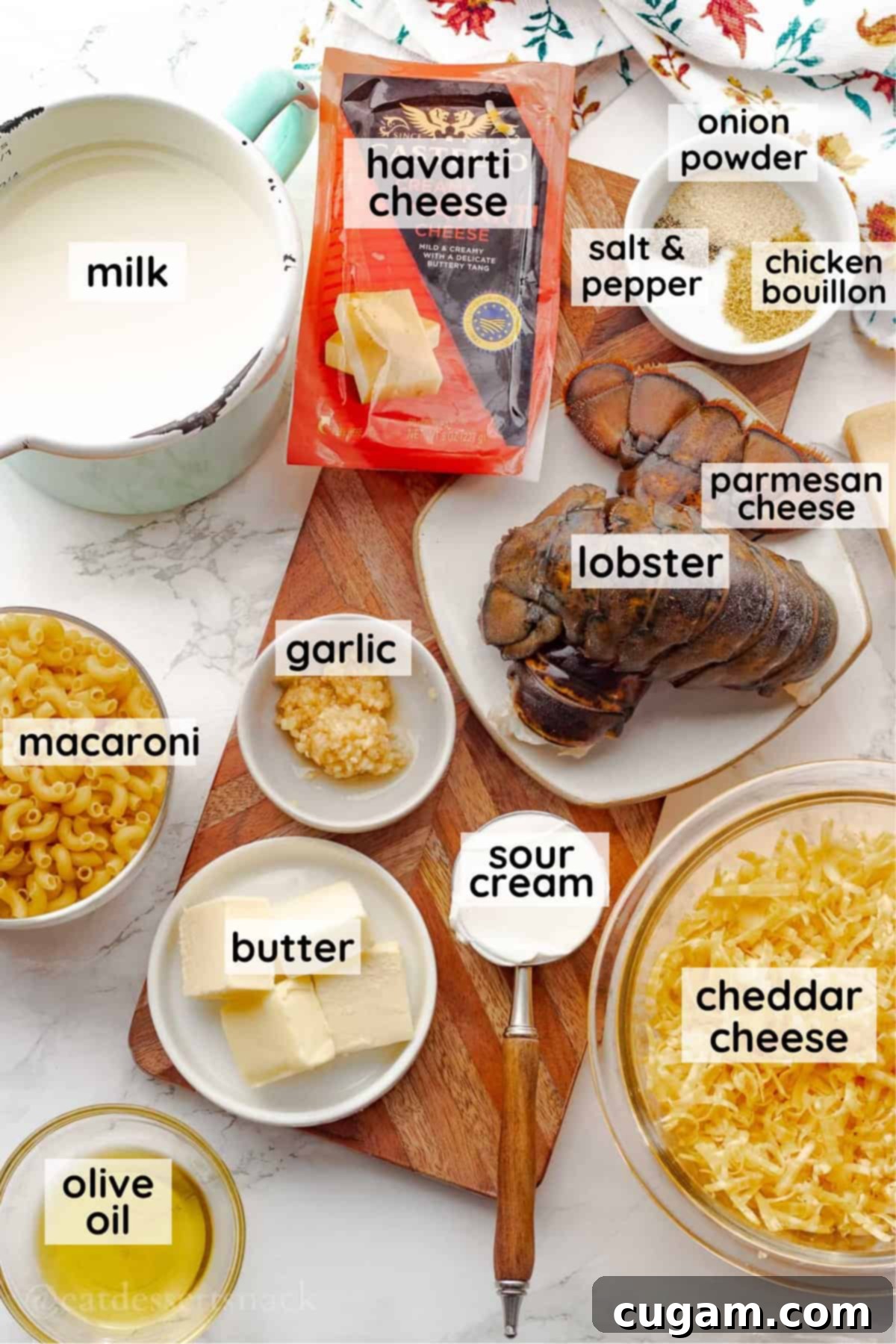 Labeled glass bowls containing essential ingredients for baked lobster mac and cheese, neatly arranged on a rustic wooden cutting board.