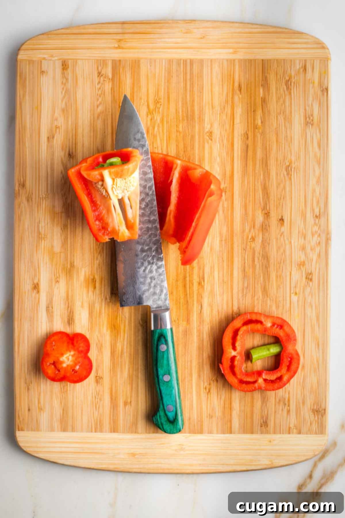 Israeli Corn and Pickle Salad 7 A red bell pepper being prepared on a cutting board, with the core and seeds carefully removed before dicing.