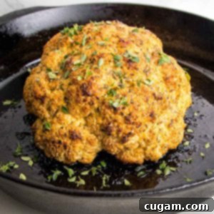 Golden brown whole roasted cauliflower, sprinkled with fresh herbs.