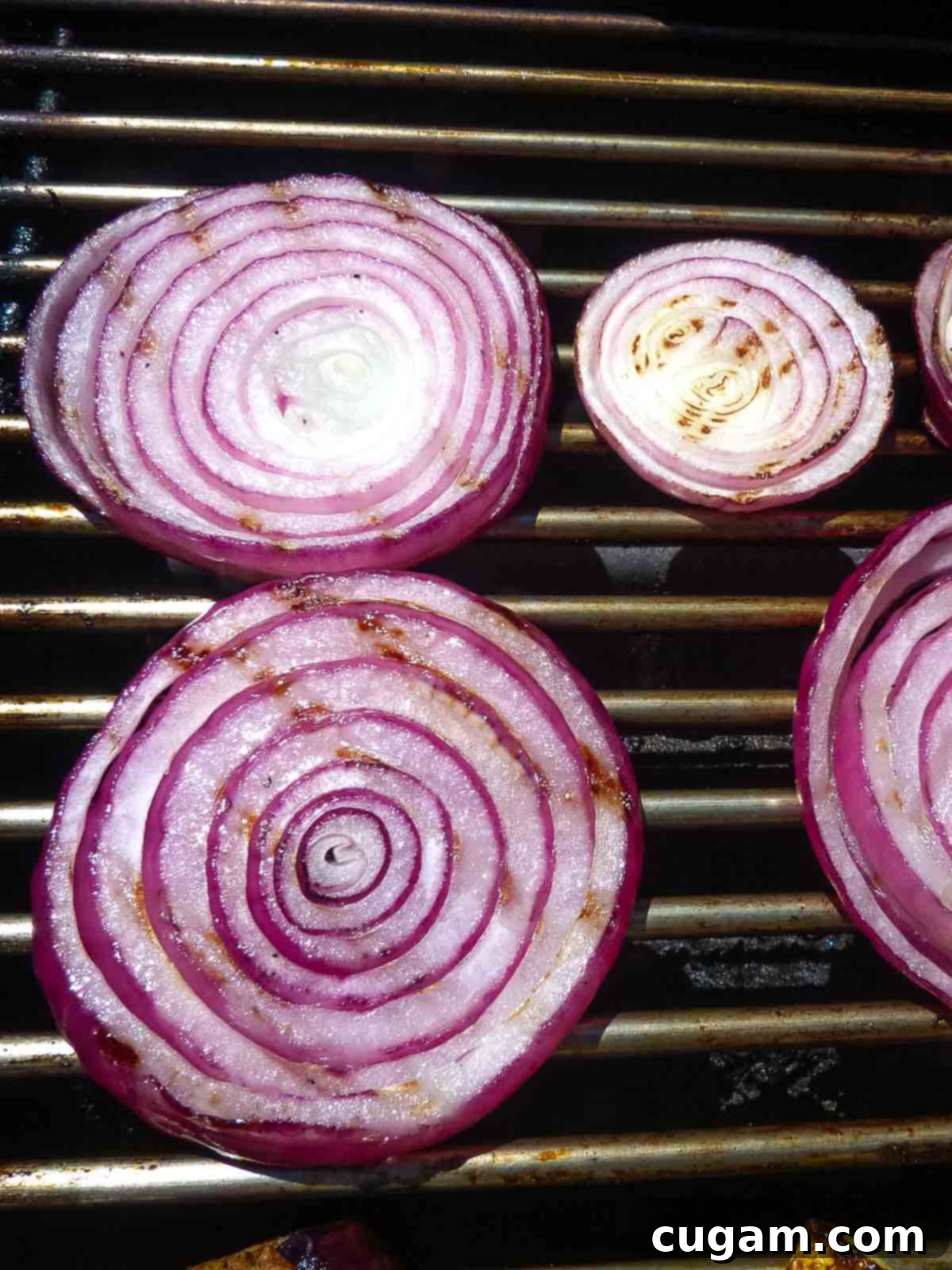 A hand using grilling tongs to carefully flip a slice of grilled zucchini, revealing excellent, dark grill marks on the cooked side.