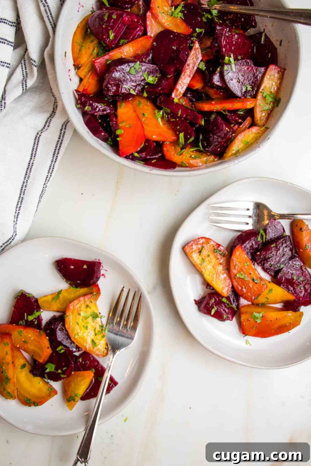 Roasted beet salad sprinkled with chopped parsley in a white bowl. Two small plates with servings of beet salad.
