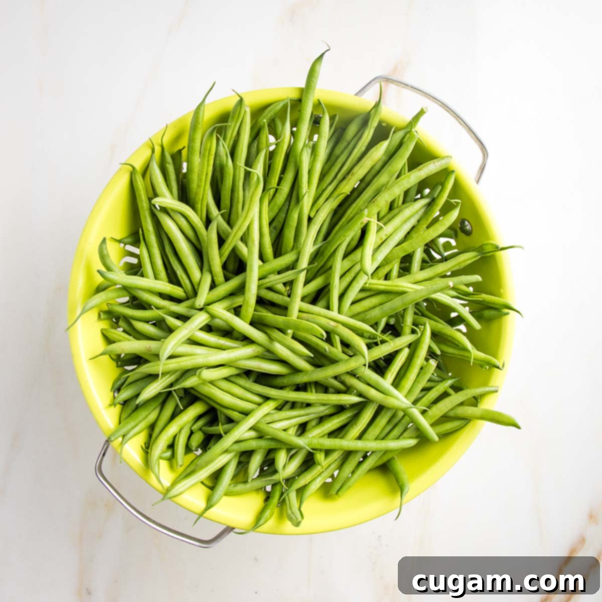 Effortless Green Beans with Toasted Almonds 3 Lime green colander filled with green beans.