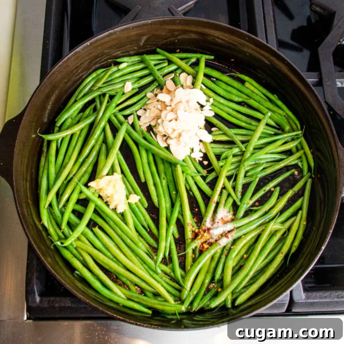 Effortless Green Beans with Toasted Almonds 8 Green beans in a cast iron pan with sliced almonds, crushed garlic and spices.