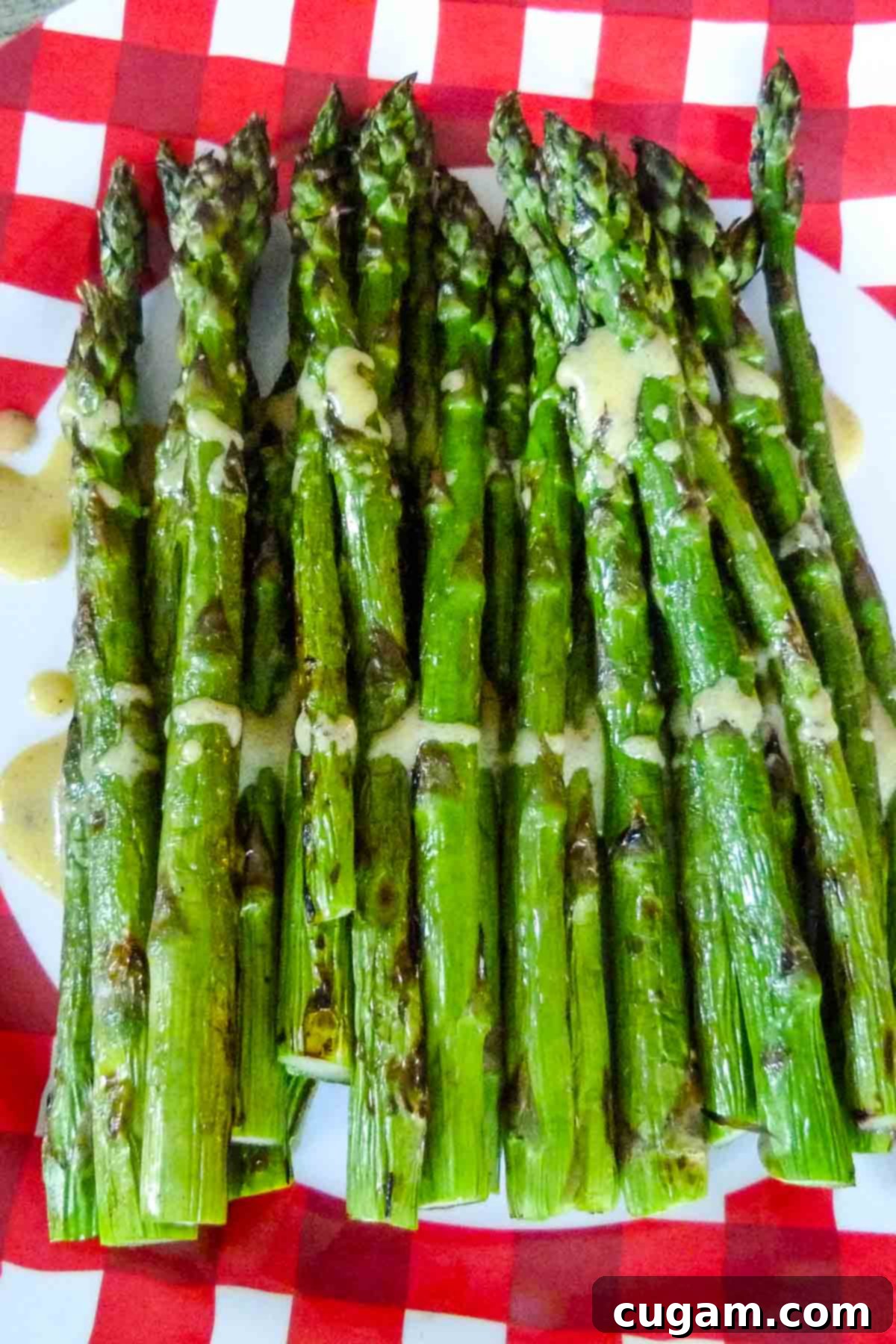 Plate of perfectly grilled asparagus spears, lightly drizzled with a vibrant, creamy mustard sauce, ready to be served.