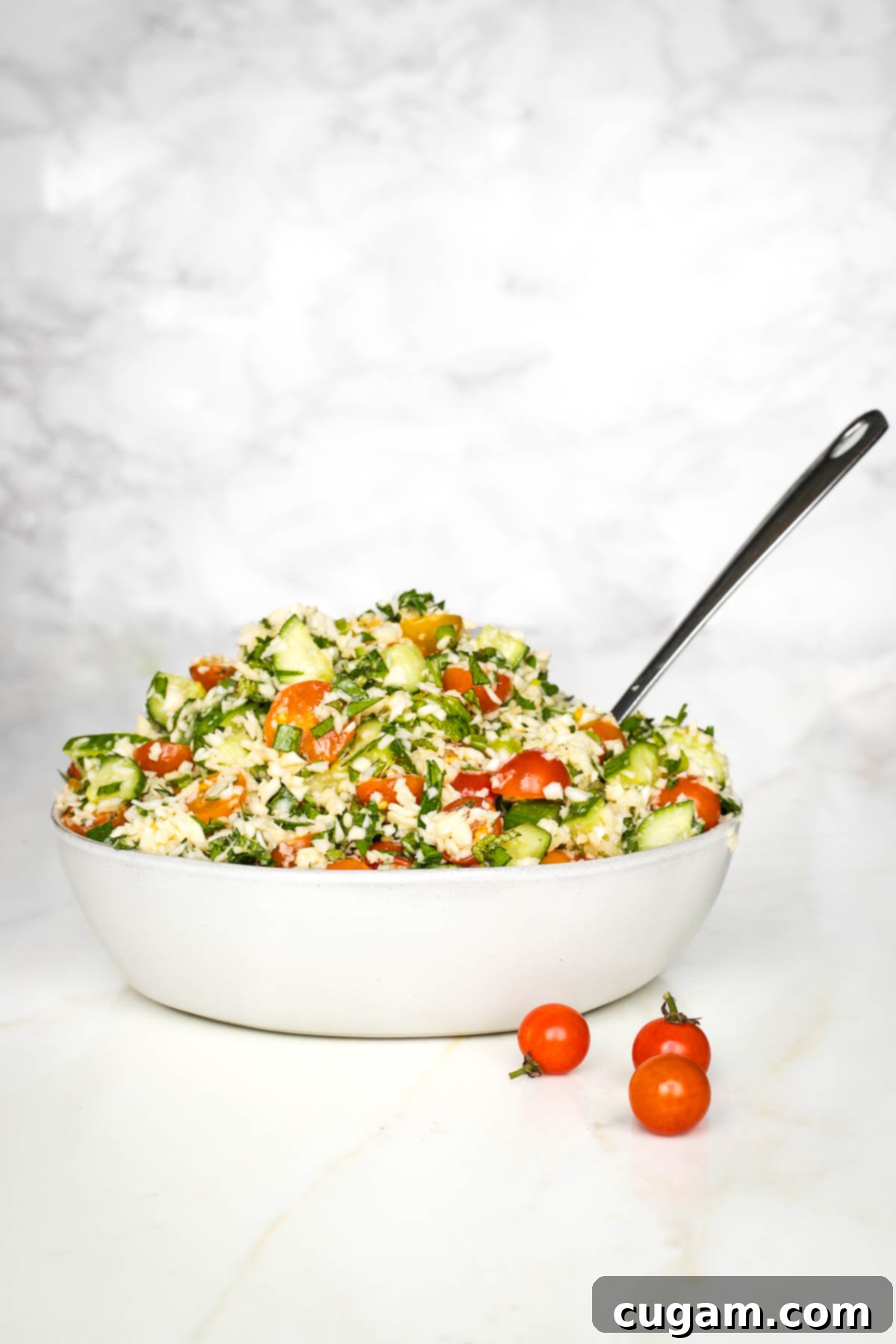 Bowl of colorful tabbouleh with tomatoes, fresh herbs, and scallions. 