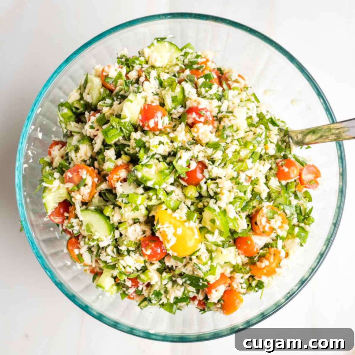 Tabbouleh salad with bright colorful tomatoes, green herbs and cucumbers and little pieces of riced parsnips.