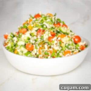 Bowl of tabbouleh with colorful tomatoes, fresh herbs, scallions and riced parsnips.