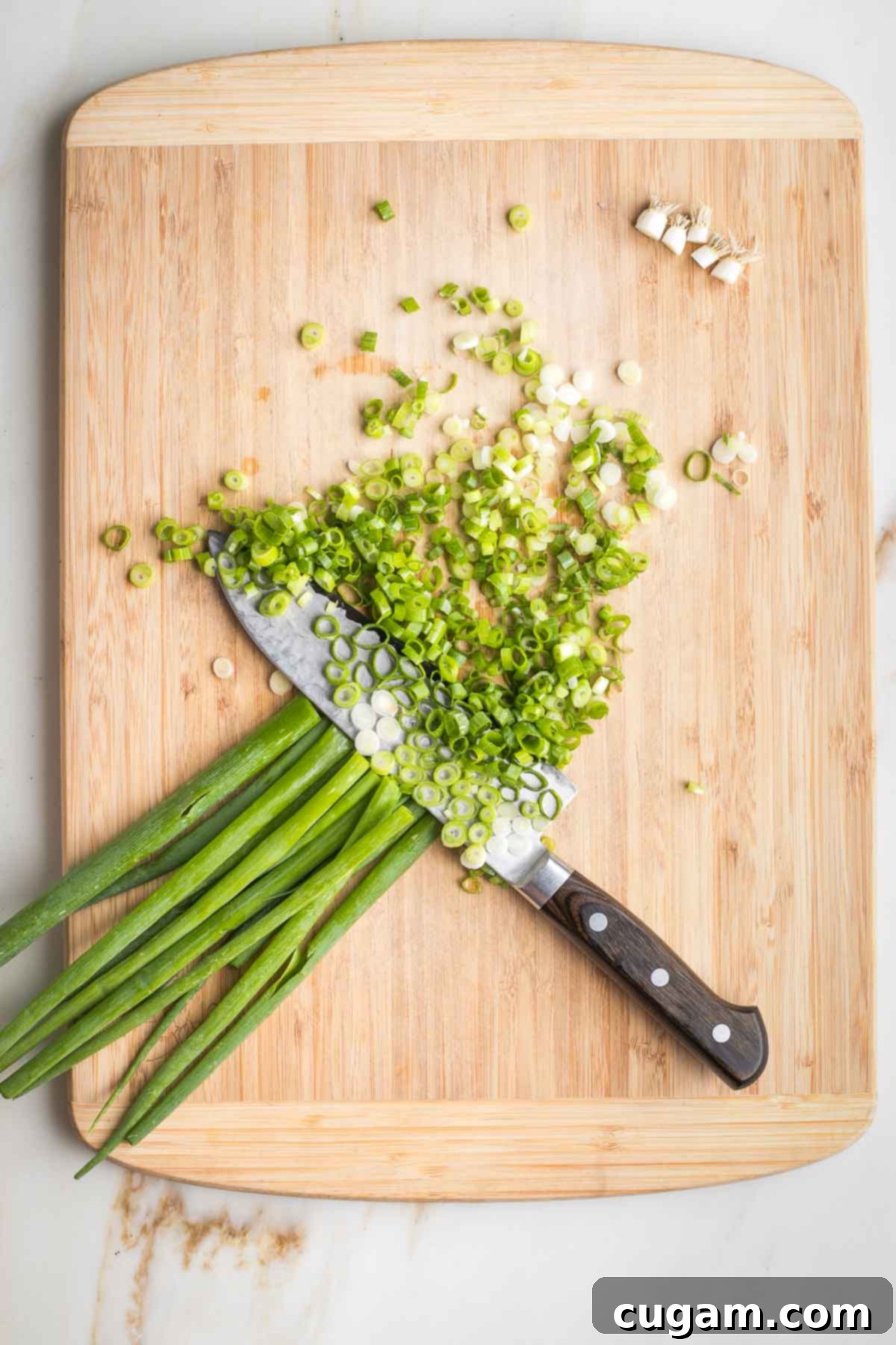 Slicing green onions on a wooden cutting board. 