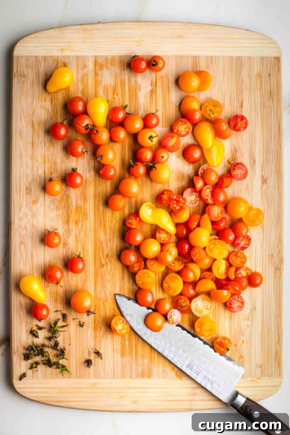 Removing stems from cherry and grape tomatoes and then cutting them in half. 