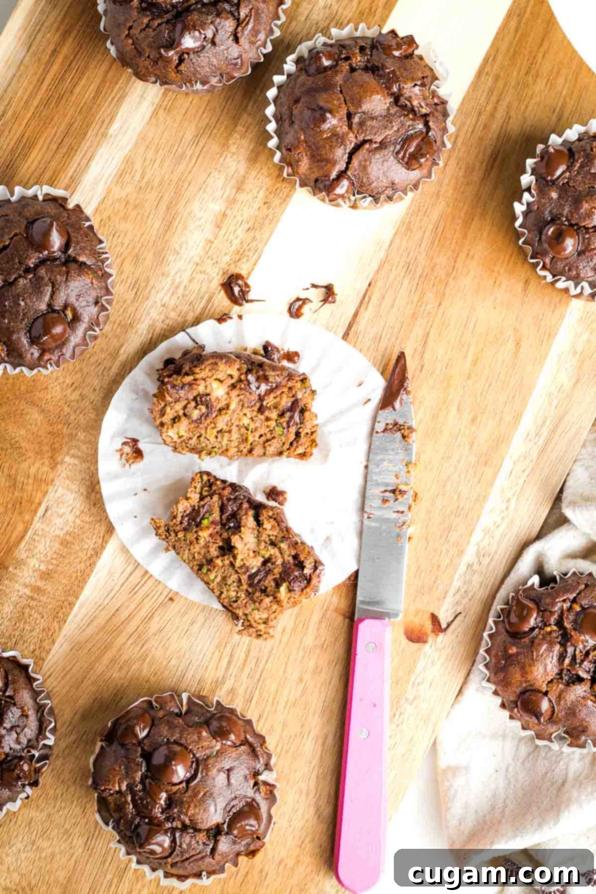 Decadent Double Chocolate Zucchini Muffins 2 A perfectly baked double chocolate zucchini muffin, cut in half to show its moist, chocolate-chip-studded interior, resting in a paper wrapper.
