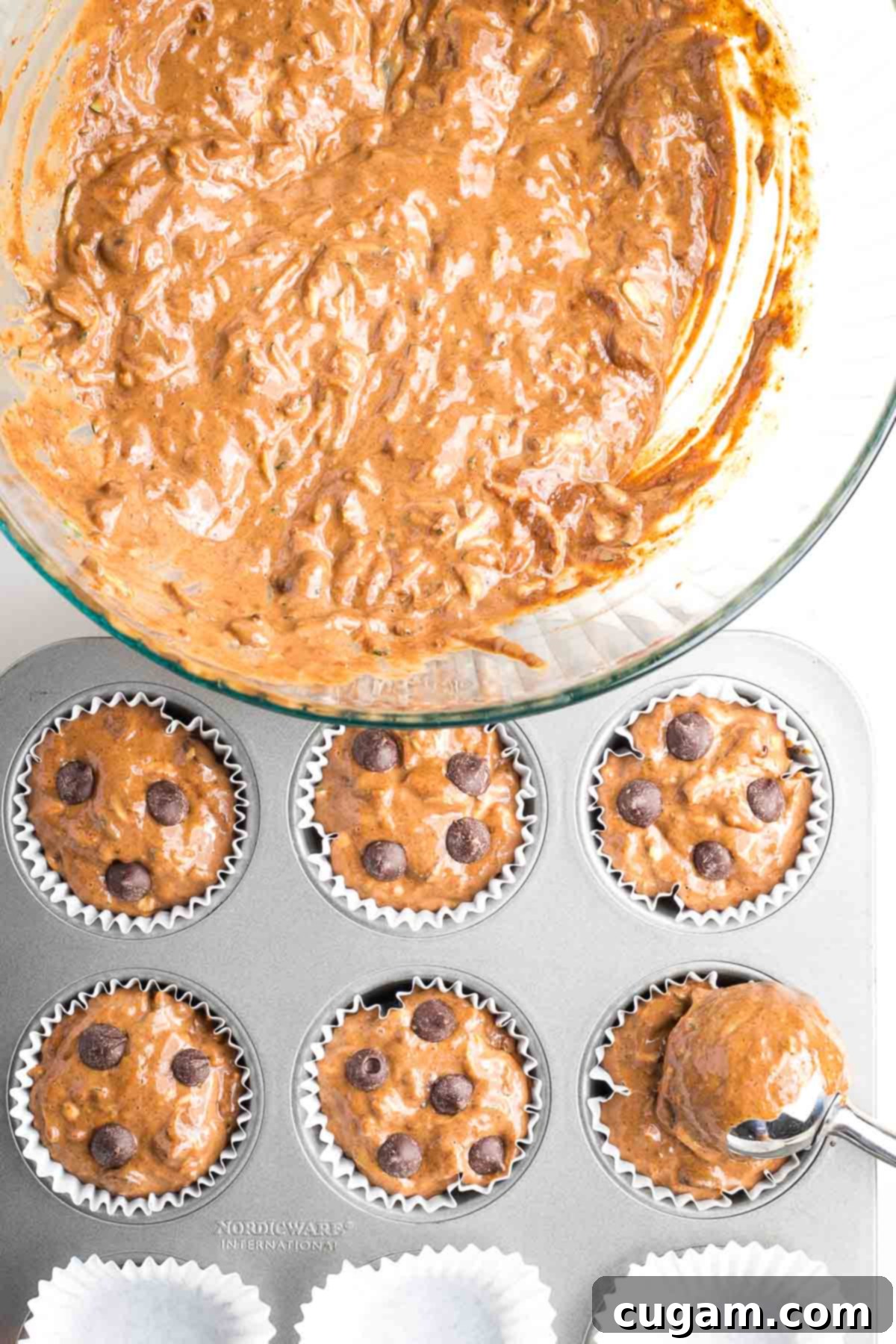 Decadent Double Chocolate Zucchini Muffins 10 Muffin batter being scooped into lined muffin tins, with extra chocolate chips sprinkled on top for a delightful finish.