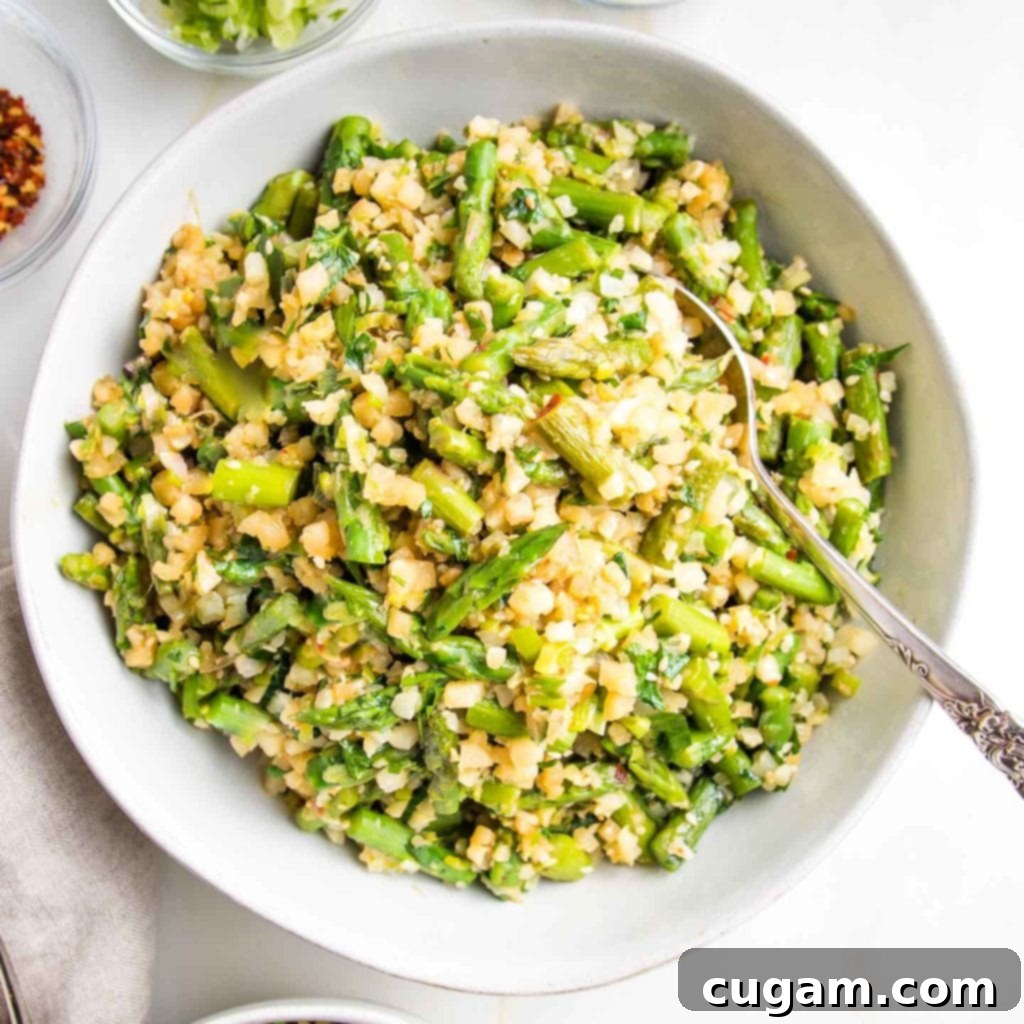 Large white serving bowl filled with Cauliflower rice and asparagus.