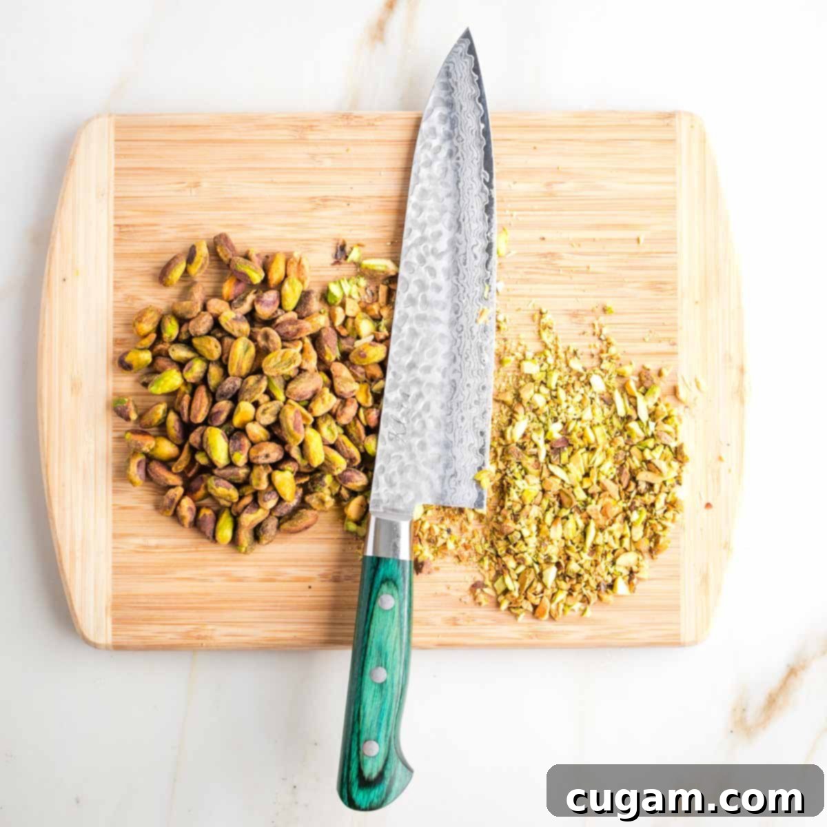 Cutting board with some whole and some already chopped pistachios. 