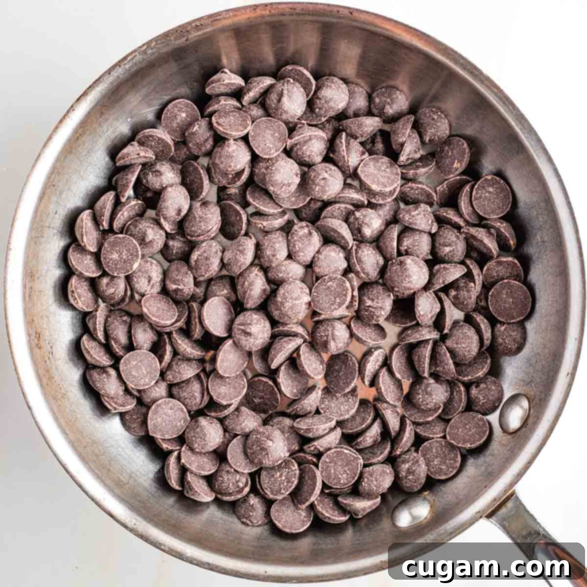 Dark chocolate chips in a small stainless steel skillet.
