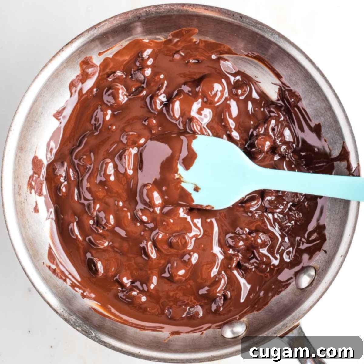 Melting chocolate on the stove in a skillet while stirring with a silicone spatula. 